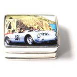 A silver and enamel pill box decorated with a Porsche 550. Weighs 20g. Measures 3cm.