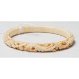 A 19th Century Chinese carved ivory bangle of typical circular form featuring stone inset eyes and a