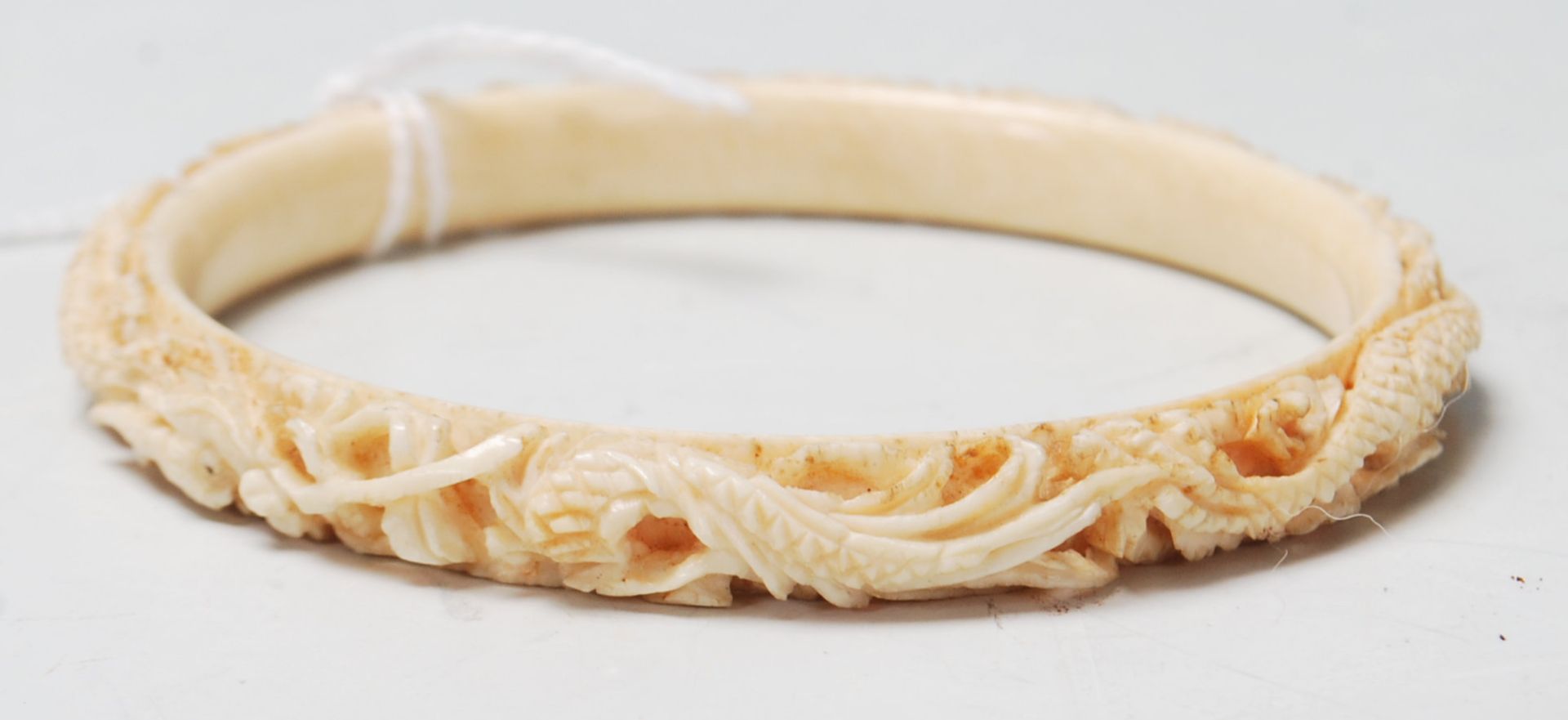 A 19th Century Chinese carved ivory bangle of typical circular form featuring stone inset eyes and a