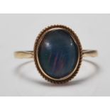 A hallmarked 9ct gold ring set with an oval opalescent cabochon with rope twist to the mount.