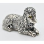 A sterling silver figurine of a poodle dog in a sitting position with yellow glass eyes. Measures: