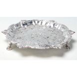 A George II silver hallmarked salver of circular form with scalloped edge being raised on hoof feet.