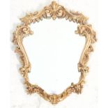 An antique style Rococo wall mirror of scrolled form. The central mirror panel held within a faux