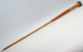 A late 20th Century gentleman's walking stick / cane having a wooden ball handle with a carving of a