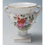 A Royal Worcester porcelain twin handled small vase urn with white ground having chintz foliate