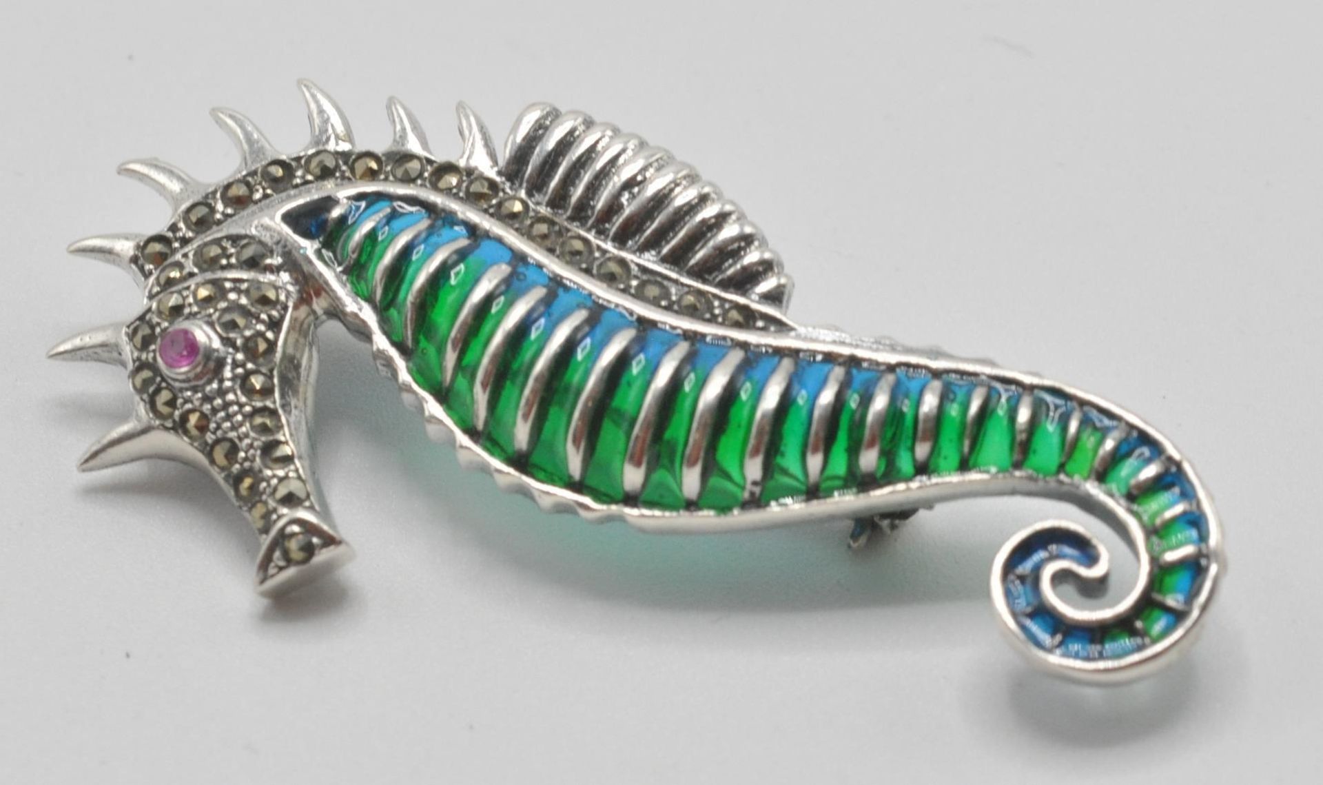 A silver 925 plique a jour pendant . brooch in the form of a seahorse with red stone eye having