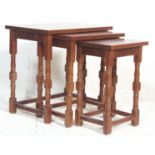 A set of antique style teak wood nest of graduating tables having a flared top over turned block
