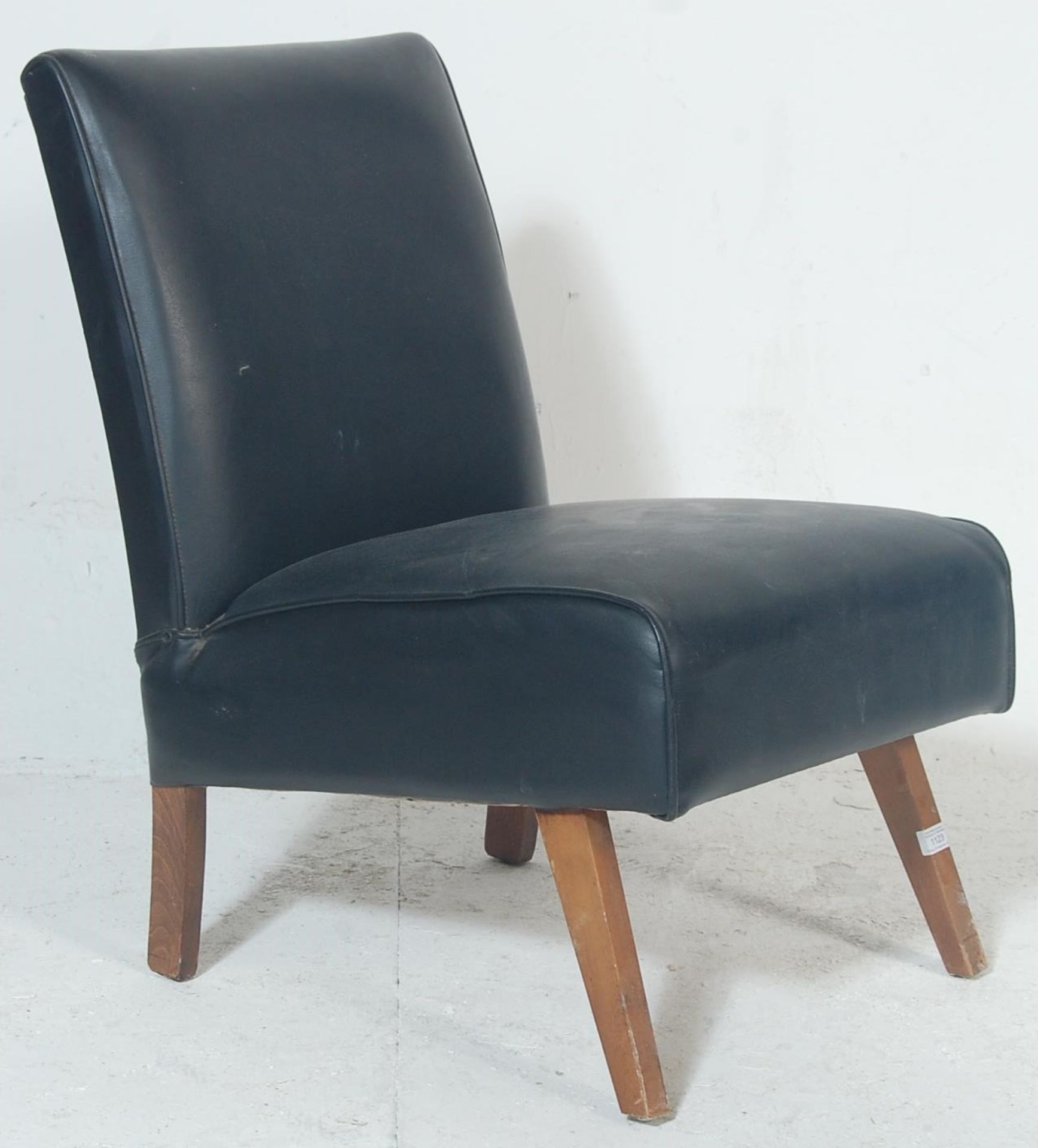 A vintage retro late 20th century bedroom chair having black leather upholstery raised on angular