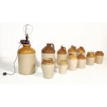 A collection of early 20th century antique stoneware advertising flagons. Of various shapes and