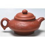 A 20th Century Chinese Yi Xing red clay teapot raised on a footed base with engraved bamboo design