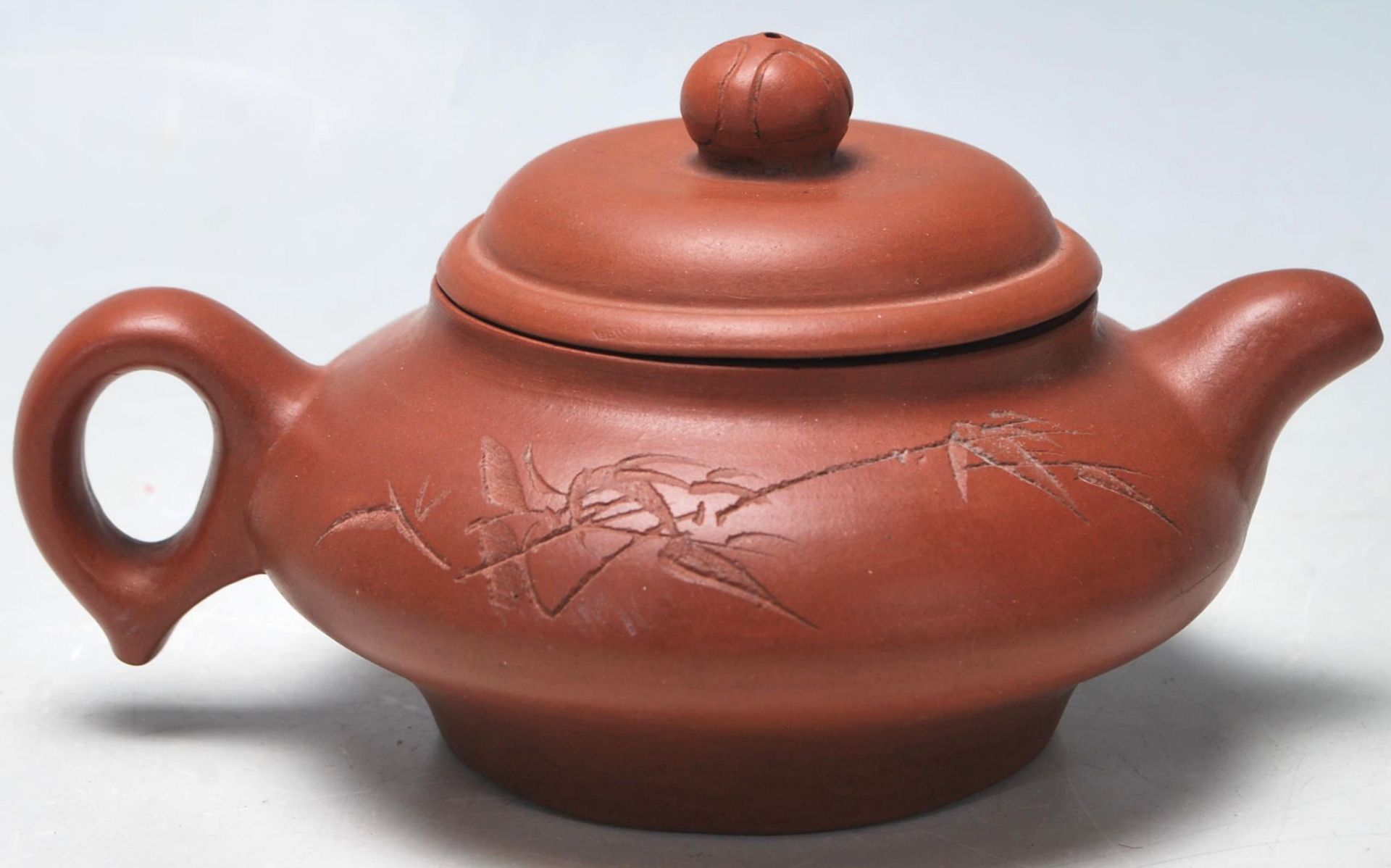 A 20th Century Chinese Yi Xing red clay teapot raised on a footed base with engraved bamboo design