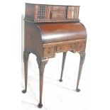 A 1920s Queen Anne revival cylinder bureau being raised on tall cabriole legs with pad feet and