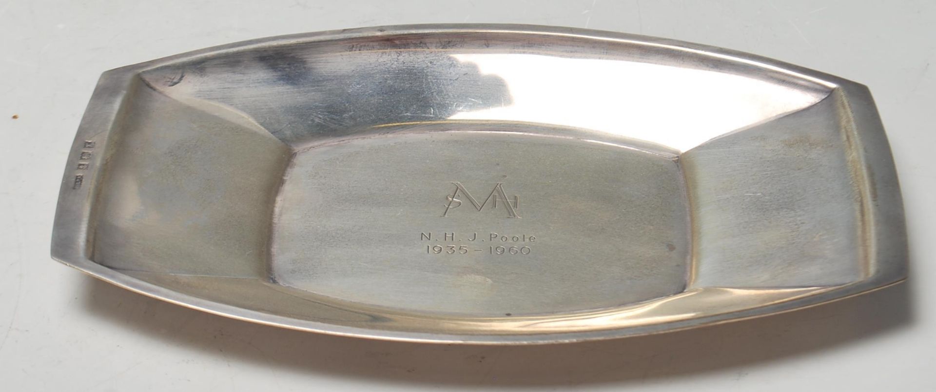 A silver hallmarked dish of lozenge form with raised edges. Central notation for SMH - NHJ Poole
