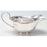 A silver English hallmarked gravy boat having flat ban curved handle and flat plinth base with
