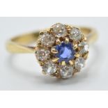 A hallmarked 18ct gold diamond and sapphire cluster ring being set with a central round cut