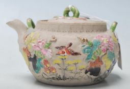 A antique Chinese believed 19th century clay teapot with coloured raised natural motif. Marked