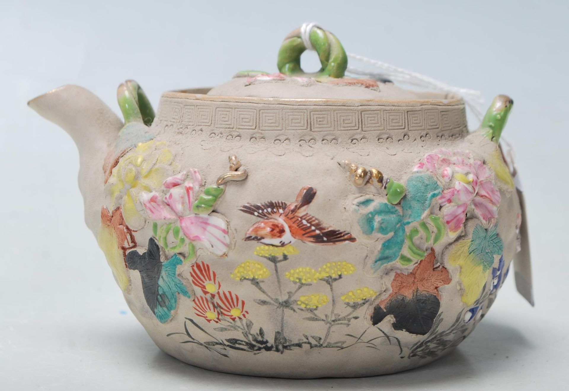 A antique Chinese believed 19th century clay teapot with coloured raised natural motif. Marked