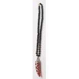 A contemporary Chinese beaded necklace having a black bead necklace with a red stone tooth shaped