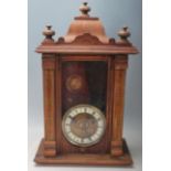 A vintage antique style wall clock having a pediment top over a glazed door with a brass and white