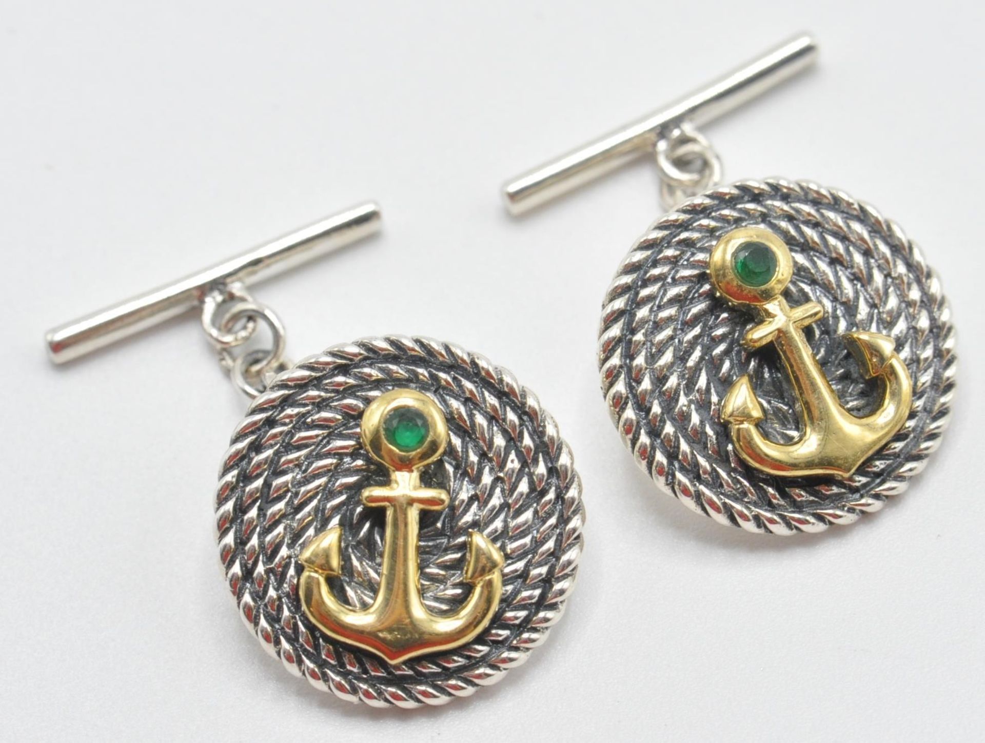 A pair of sterling silver gentleman's cufflinks having embossed yellow metal anchors and green stone