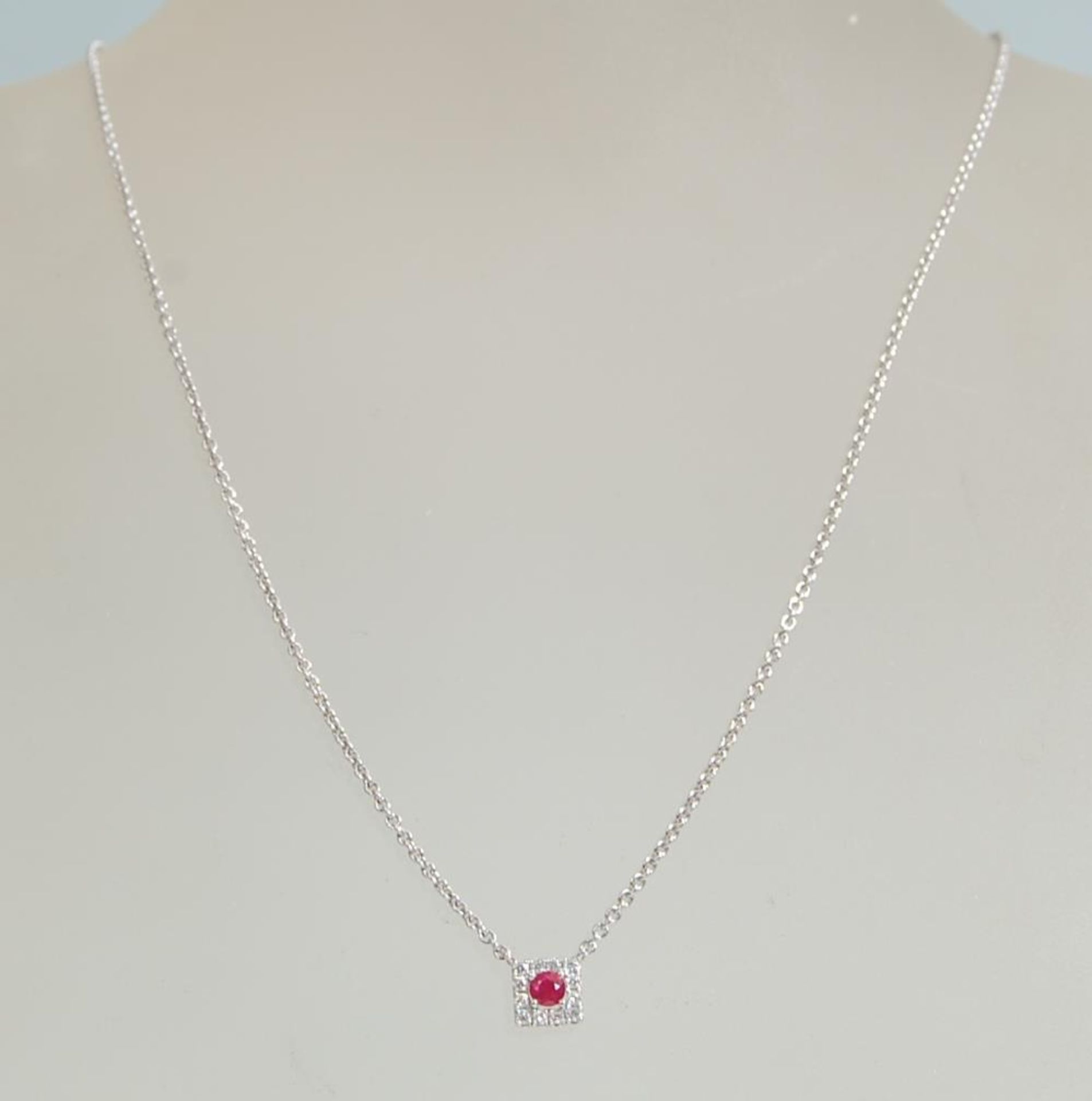 An 18ct white gold necklace pendant set with a a central ruby in a square halo set with diamond