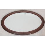 A good early 20th century antique wall hanging mirror in oval shaped with bevelled glass and oak