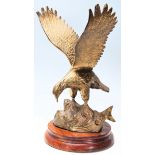 A large 20th century brass cast figurine of an American Eagle in flight being set to a wooden