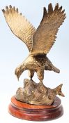 A large 20th century brass cast figurine of an American Eagle in flight being set to a wooden