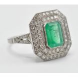 A platinum emerald and diamond cocktail ring. The ring set with a central octagon cut emerald having