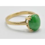 A hallmarked 18ct gold ring being prong set with a oval green jade cabochon and engraved