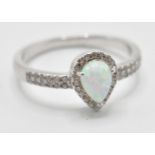 A stamped 925 silver ring having a central opal stone in a shape of teardrop and CZ accent stones.