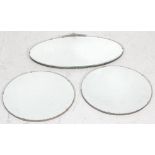 A group of three early 20th century Art Deco wall hanging mirrors. An oval beveled glass mirror with