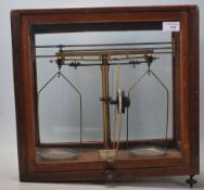 A pair of mid century wooden cased scientific scales in brass set to a black glass base with