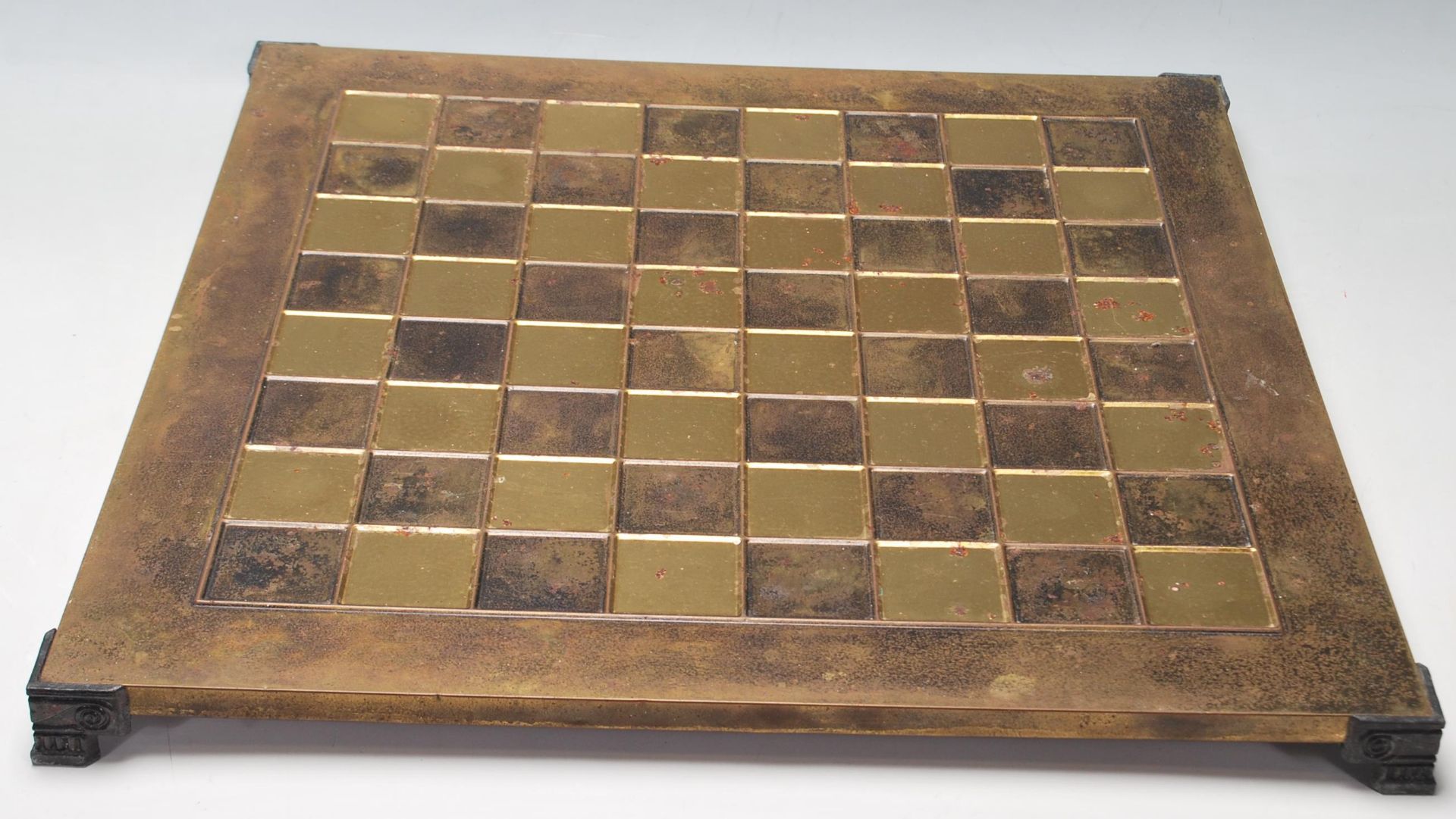 A 20th Century brass chess board raised on bracket feet with ebonised squares together complete with