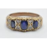 A 9ct gold ladies ring being set with three oval cut blue sapphires with illusion set diamond accent