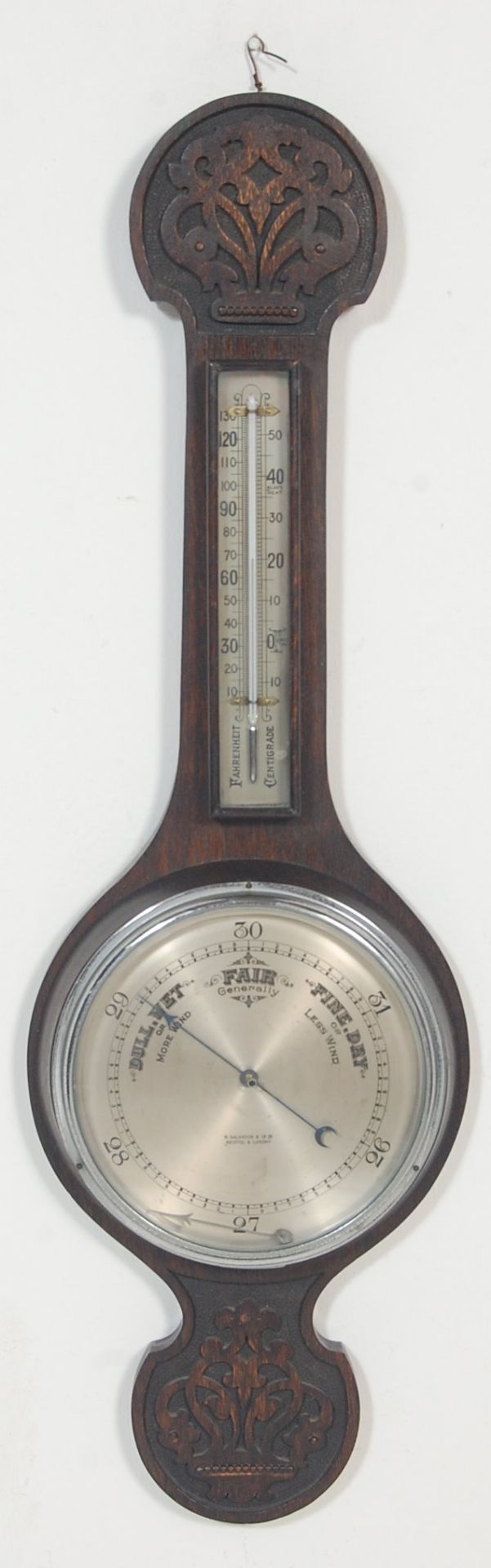 An early 20th century carved oak aneroid wall barometer. The barometer of banjo form having
