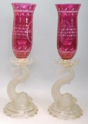 A pair of early 20th Century Baccarat Dauphin Candlesticks having cut glass cranberry hurricane