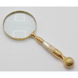A 20th Century desktop magnifying glass having a white brass banded handle with inlaid mother of