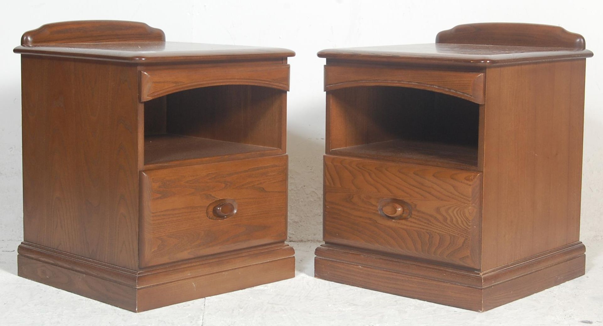 A pair of 20th century Ercol style elm  bedside cabinets by Jentique. Each being raised on plinth