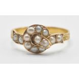 A 19th Century Victorian knot design ring being set with half pearls in a ribbon style mount with