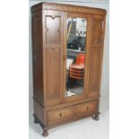 An early 20th Century Edwardian wardrobe having a scrolled top over a single mirrored door between