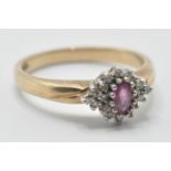 A hallmarked 9ct gold ladies ring being set with a central oval cut ruby surrounded by round cut
