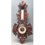 An early 20th Century French carved oak barometer decorated with a wolf, birds and foliate sprays.