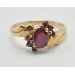 A vintage 9ct gold and ruby crossover cluster ring having a central oval cut ruby flanked by six