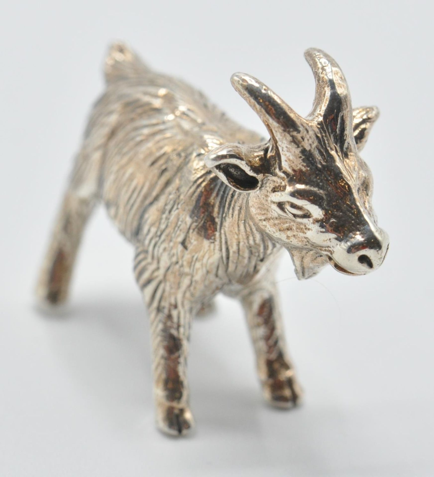 A contemporary sterling silver miniature figurine of a goat. Marked Sterling. Measures: 2cm long,