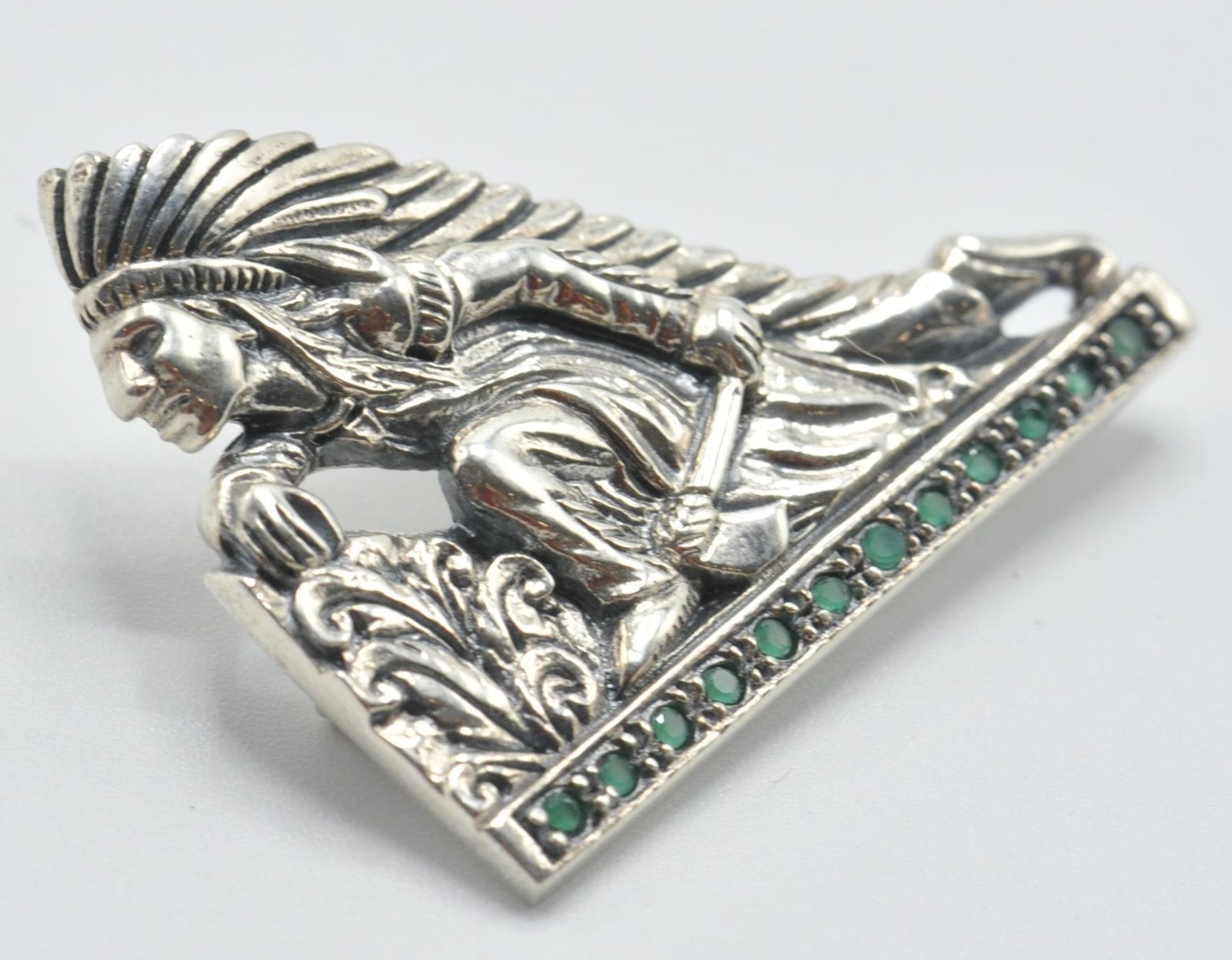 A stamped sterling silver brooch in the form of a Native American fighter wearing a feather