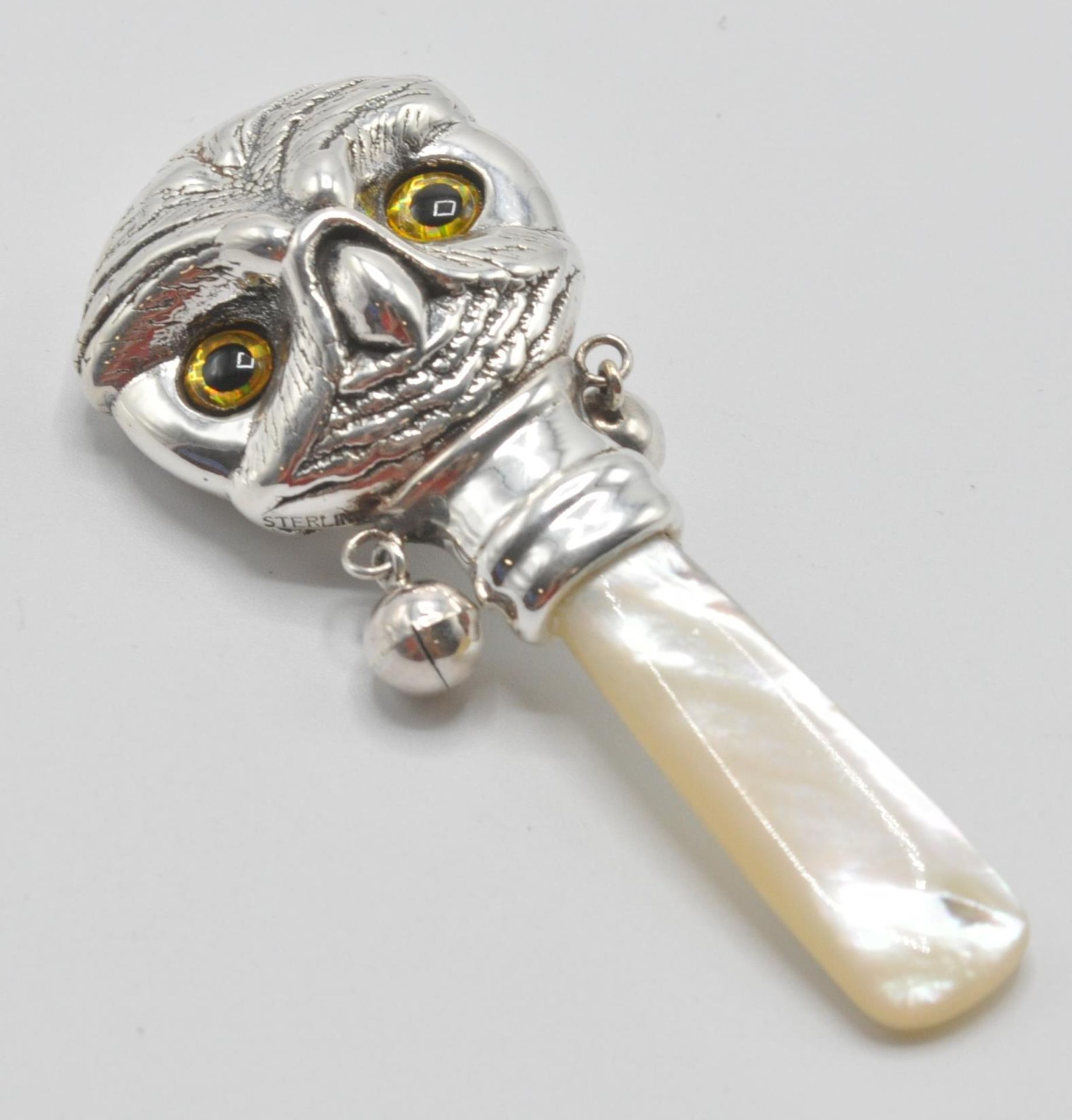 A silver babies / childs rattle in the form of an owl with yellow and black glass eyes having a