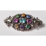 An early 20th Century silver gem set brooch being set with pink and blue sapphires, zircon,