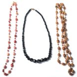 A collection of three retro vintage costume jewellery necklaces to include a brown stone and amber