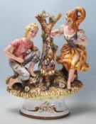 A 20th Century Italian Capodimonte style ceramic figurine depicting a boy and a girl next to a